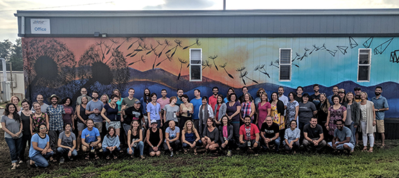 full staff photo in front of mural